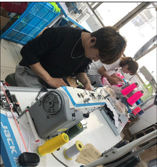 Operator sewing swimwear using specialized machinery and bright thread
