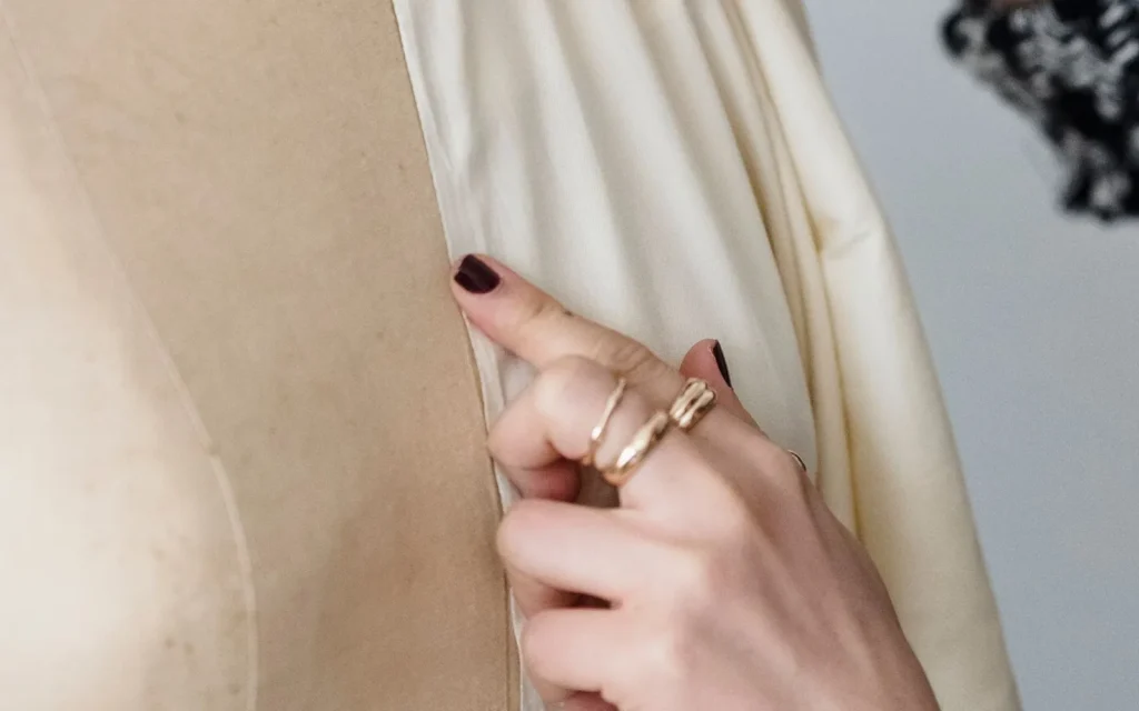 Dressmaker measuring fabric on a mannequin for quality review